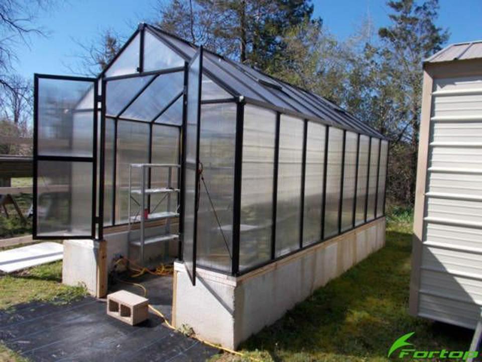 Larger model shown – Long Riverstone Monticello greenhouse on a concrete block knee wall, both doors open