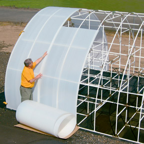 A man attaching covers on a Solexx greenhouse frame