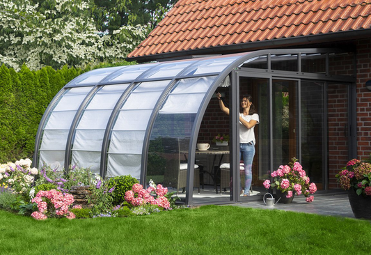 Berlin Solarveranda lean-to with curved aluminum frame and patented sliding plexiglass panels in a backyard setting