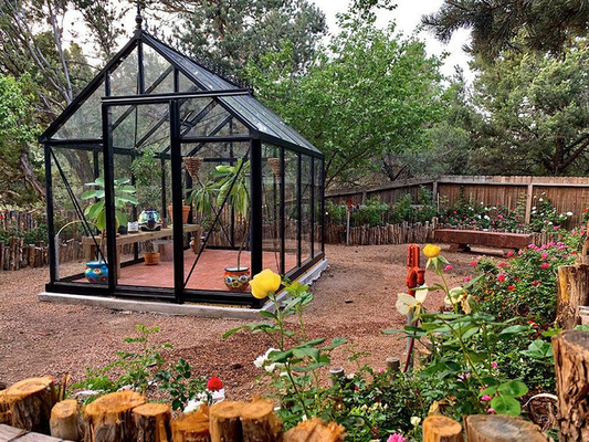 Glass greenhouse installed on a solid base, demonstrating proper anchoring for structural stability