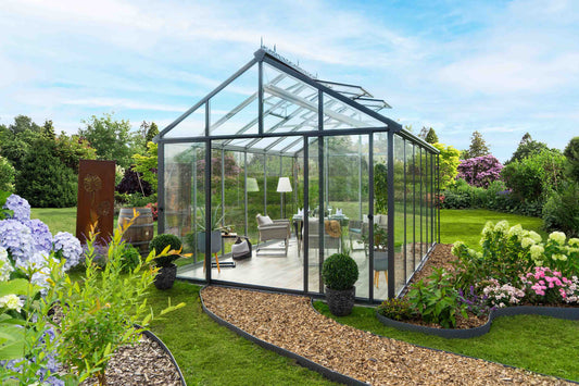 Hoklartherm Livingten insulated glass greenhouse with grey aluminum frame in a garden flower bed