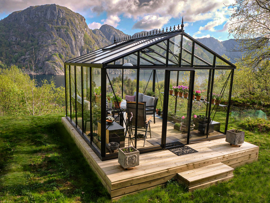Elegant glass greenhouse positioned as a landscape centerpiece overlooking scenic natural surroundings