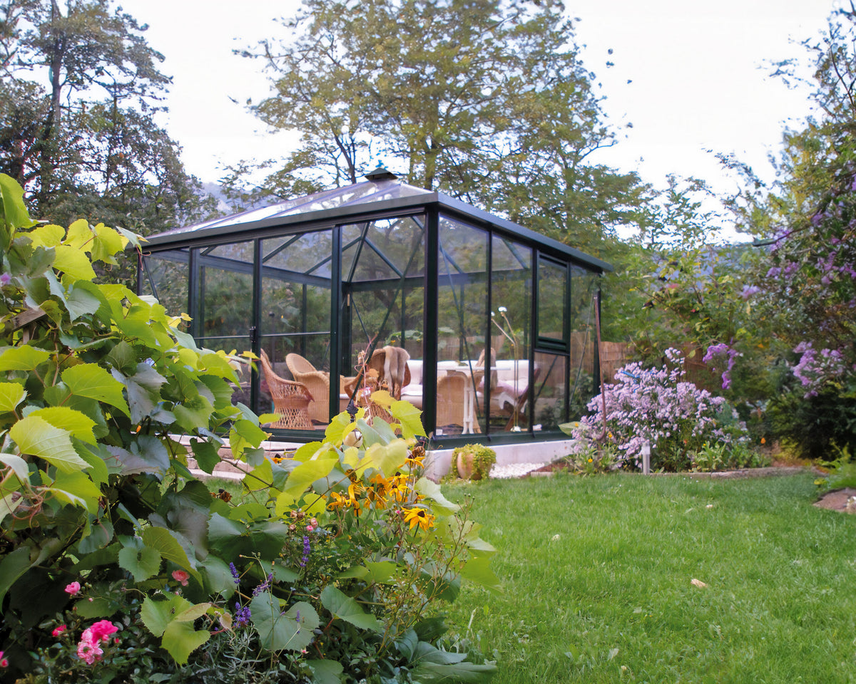 Exaco Janssens Pyramid glass greenhouse with a four-sided pyramid roof in a garden
