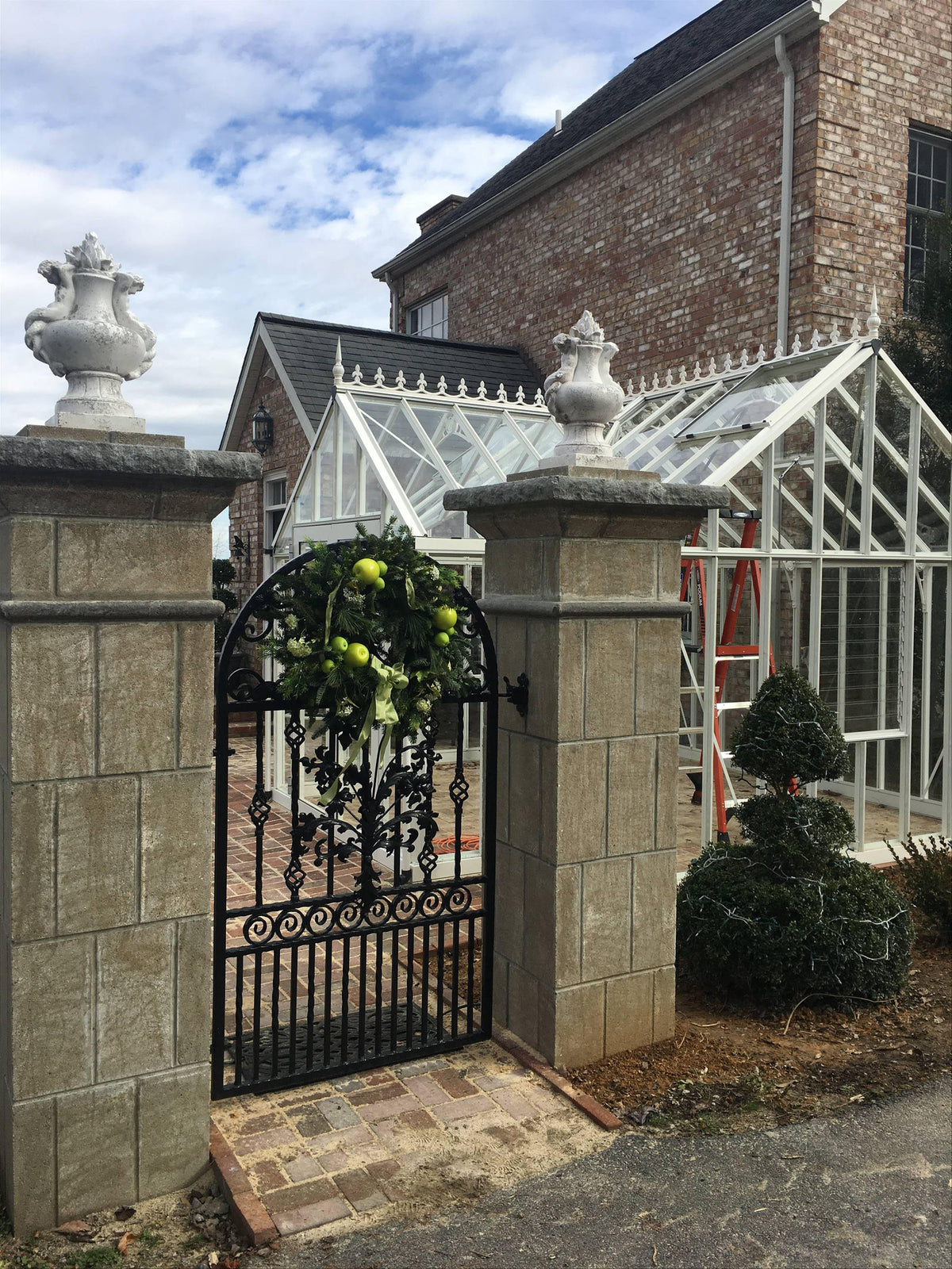 EOS greenhouse seen through stone gate pillars and an iron garden gate