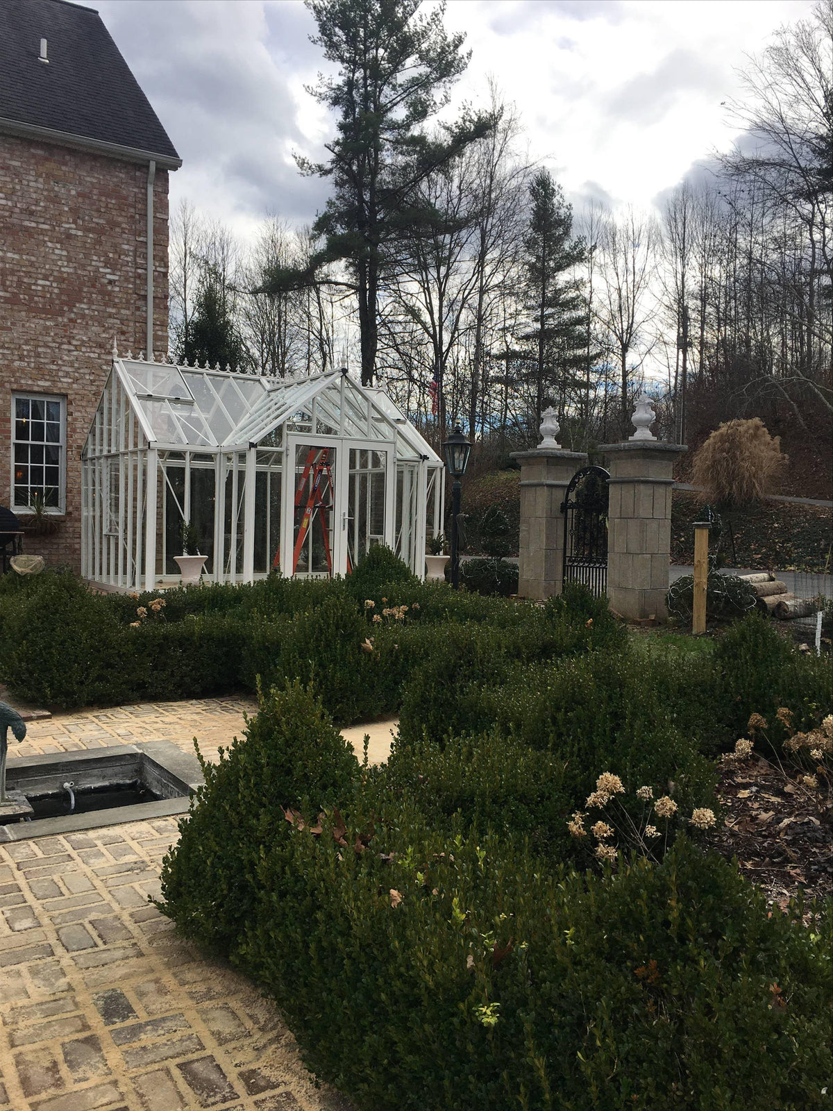 White EOS T-shaped greenhouse in a formal manor garden with clipped hedges
