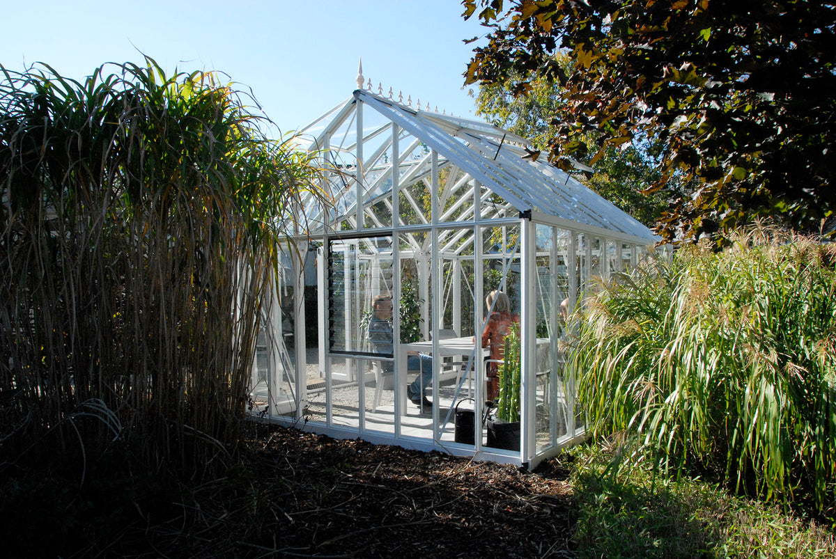 Side view of the EOS Royal Antique Victorian greenhouse among ornamental grasses