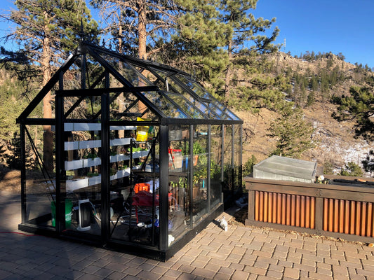 Janssens Junior Victorian glass greenhouse on a hillside patio (8x13 J-VIC 24 shown)
