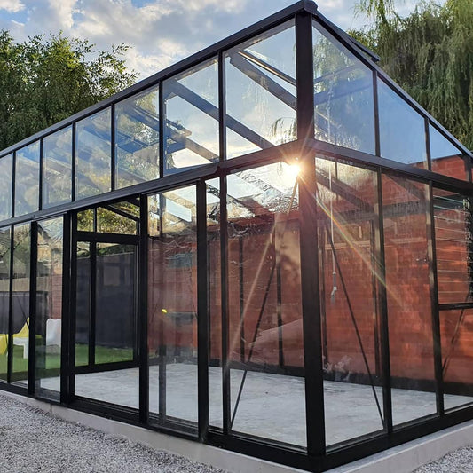Janssens Modern M36 10x20 black glass greenhouse beside a brick wall