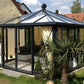 Janssens Pyramid glass greenhouse used as a garden room with curtains and lounge seating