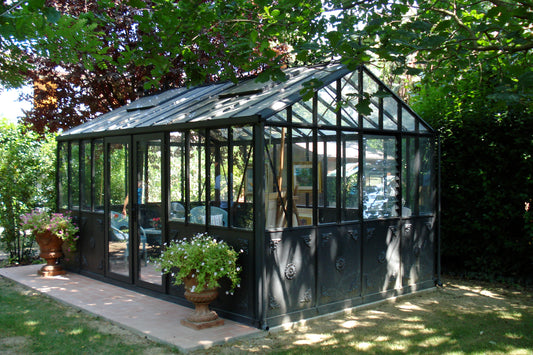 Janssens Retro Royal Victorian glass greenhouse in black, set in a landscaped garden