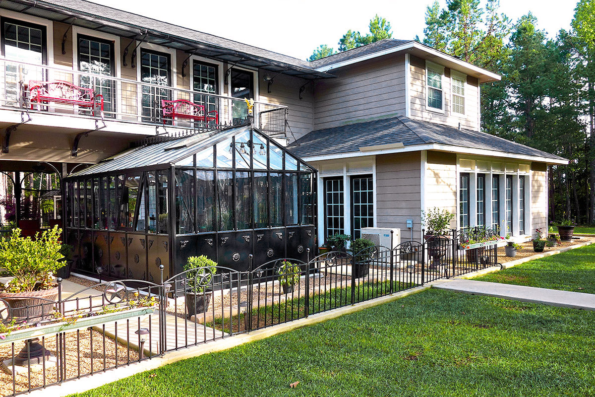 Black Retro Royal Victorian greenhouse in a home garden beside the house