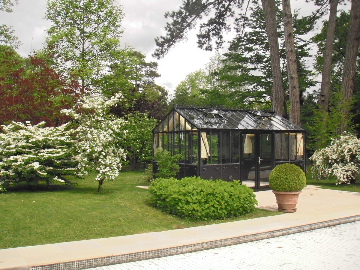 Retro Royal Victorian black aluminum greenhouse on a garden lawn