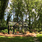Janssens T-shaped Junior Victorian Orangerie glass greenhouse in a tree-shaded garden
