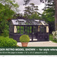 Black Janssens Retro Victorian greenhouse in a flowering garden – larger Retro model shown for style reference; the Retro 23 is 7'9" x 10'2"