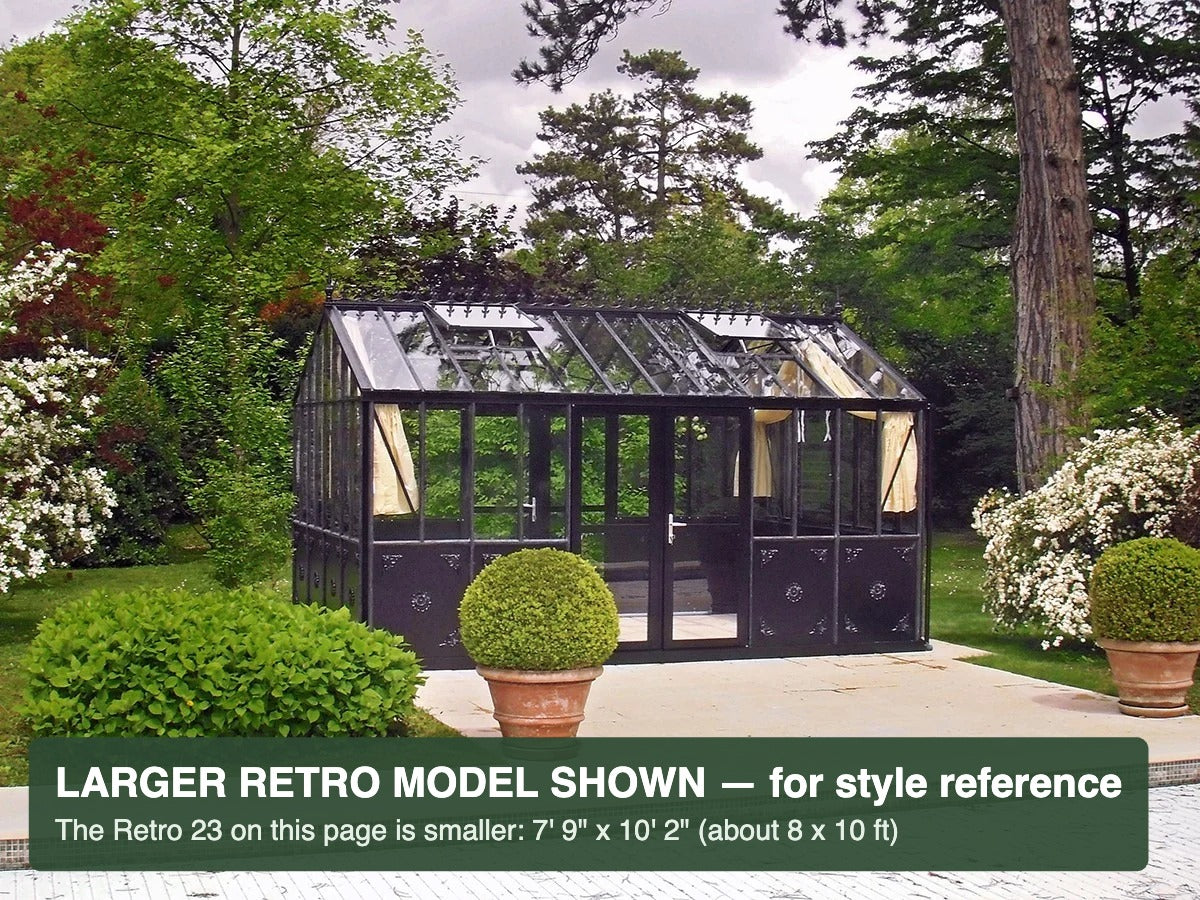 Black Janssens Retro Victorian greenhouse in a flowering garden – larger Retro model shown for style reference; the Retro 23 is 7'9" x 10'2"