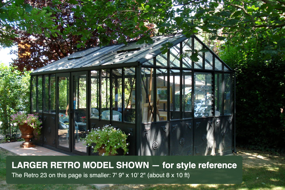 Black Janssens Retro Victorian glass greenhouse in a landscaped garden – larger Retro model shown for style reference; the Retro 23 is 7'9" x 10'2"