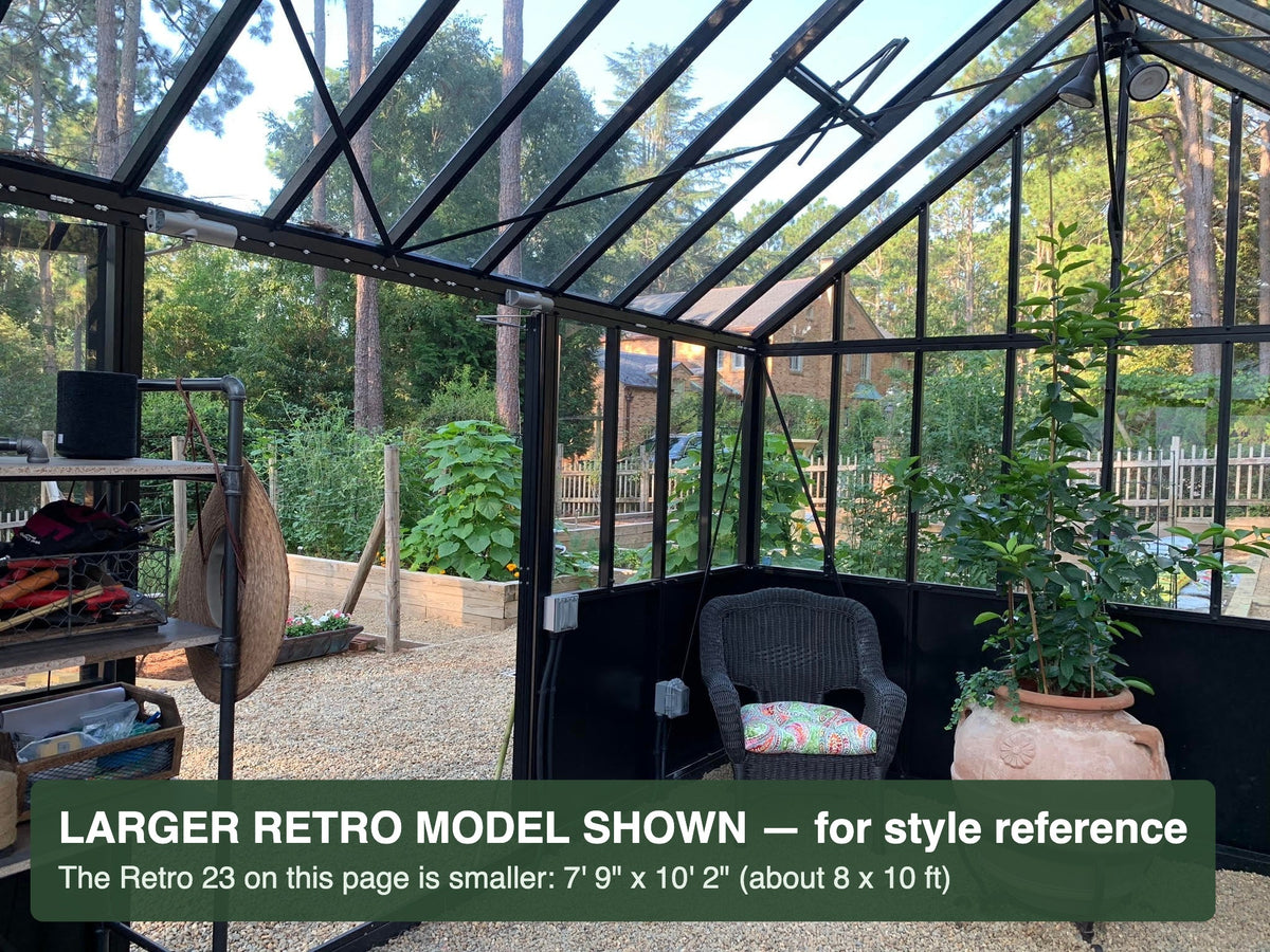 Seating area inside a black Janssens Retro Victorian greenhouse – larger Retro model shown for style reference; the Retro 23 is 7'9" x 10'2"