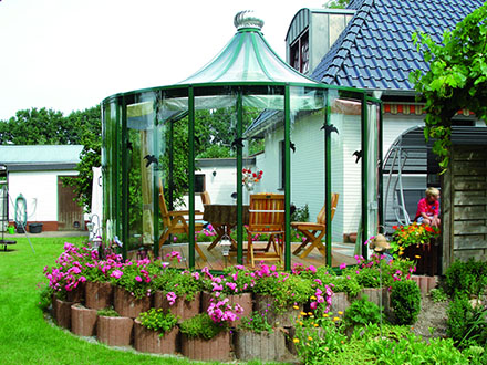 Green-frame Rondo pavilion beside a house surrounded by pink flower beds