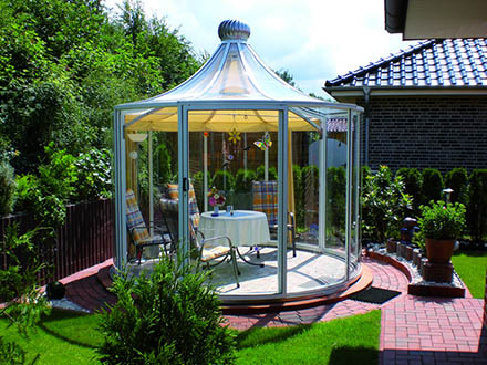 Rondo pavilion with a yellow shade curtain on a brick patio next to a house