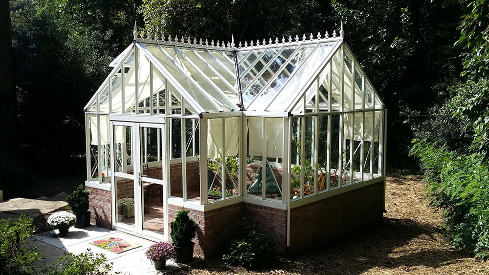 White Royal Antique Orangerie greenhouse in a shaded garden