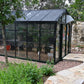 Royal Victorian VI34 glass greenhouse in a wooded garden with a stone path