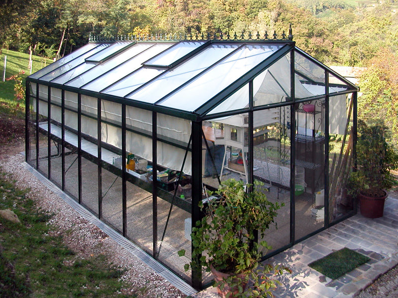 Royal Victorian VI36 glass greenhouse on a gravel base, surrounded by plants