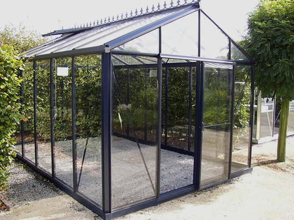 Smaller model shown – empty Royal Victorian glass greenhouse on a gravel base